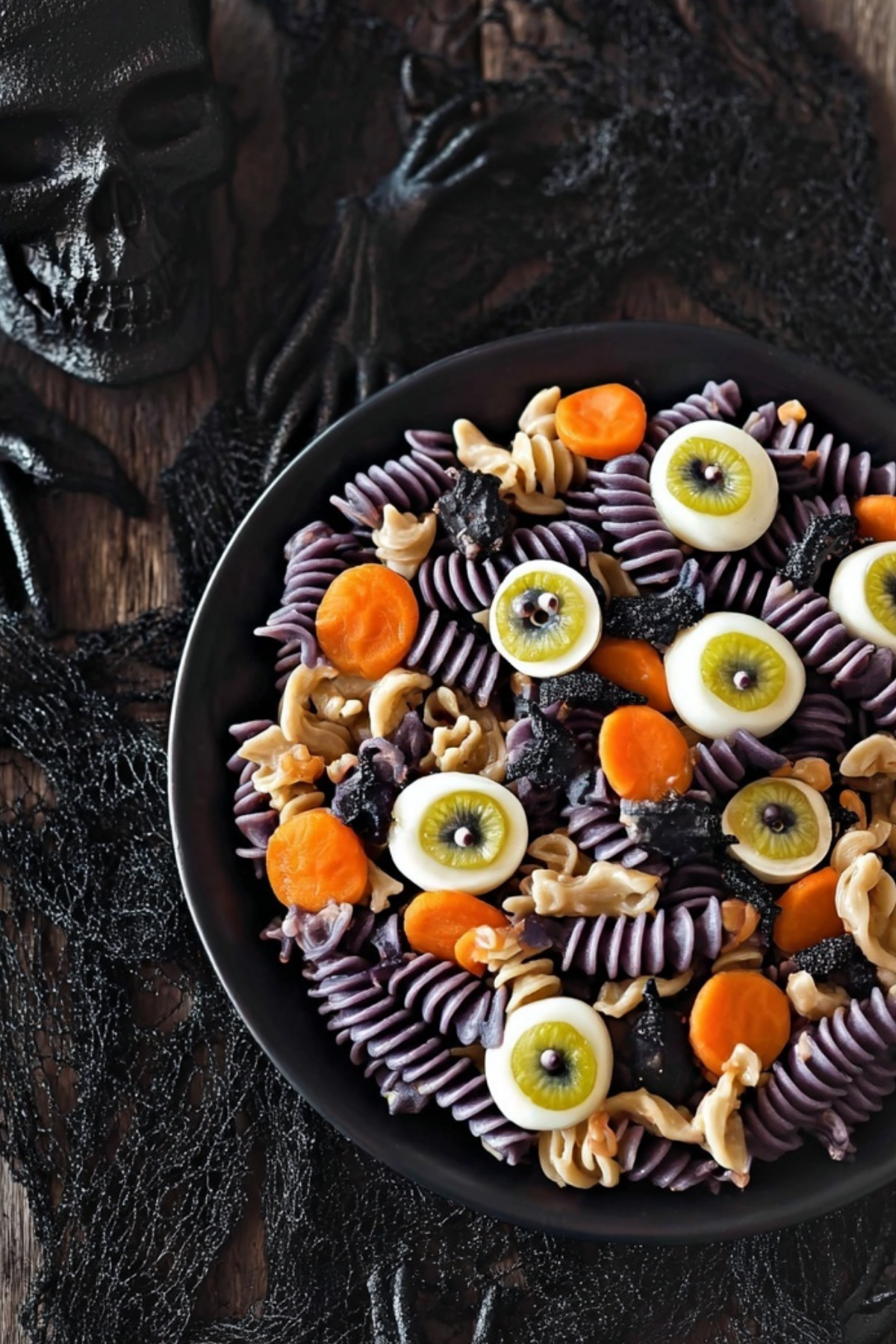 Halloween Pasta Salad with black pasta, mozzarella eyeballs, and mushroom skulls