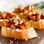 Whipped Goat Cheese Butternut Squash Bruschetta served on toasted baguette with arugula, honey, and pumpkin seeds.