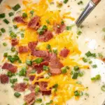 Crockpot potato soup in a bowl with bacon, cheese, and green onions