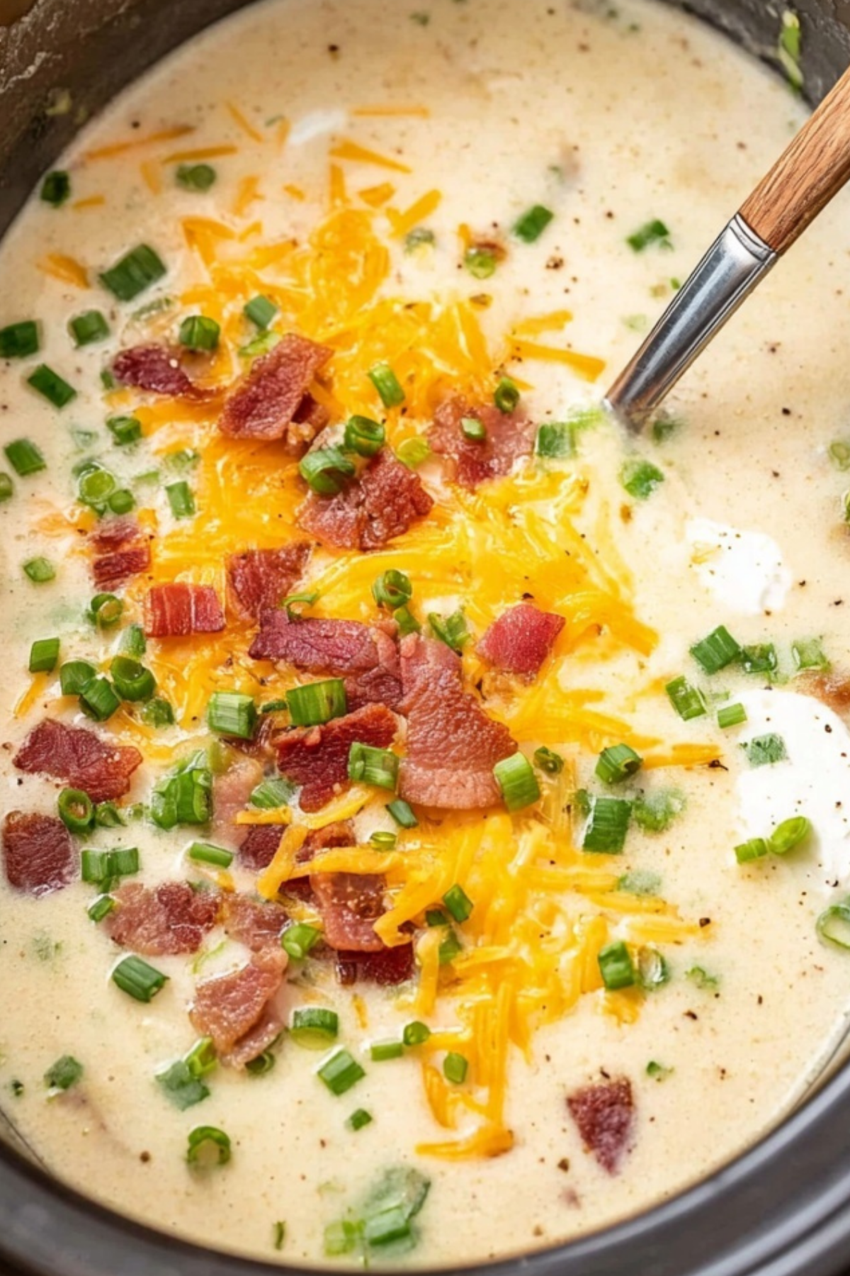 Crockpot potato soup in a bowl with bacon, cheese, and green onions