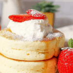 Fluffy Japanese Soufflé Pancakes stacked with whipped cream and fresh berries