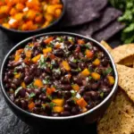 Halloween Bean Dip served with blue corn chips in black bowl