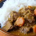 Slow cooker coconut curry beef stew in a bowl with rice