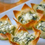 Spinach-Artichoke Dip Wonton Cups baked in muffin tin with creamy filling
