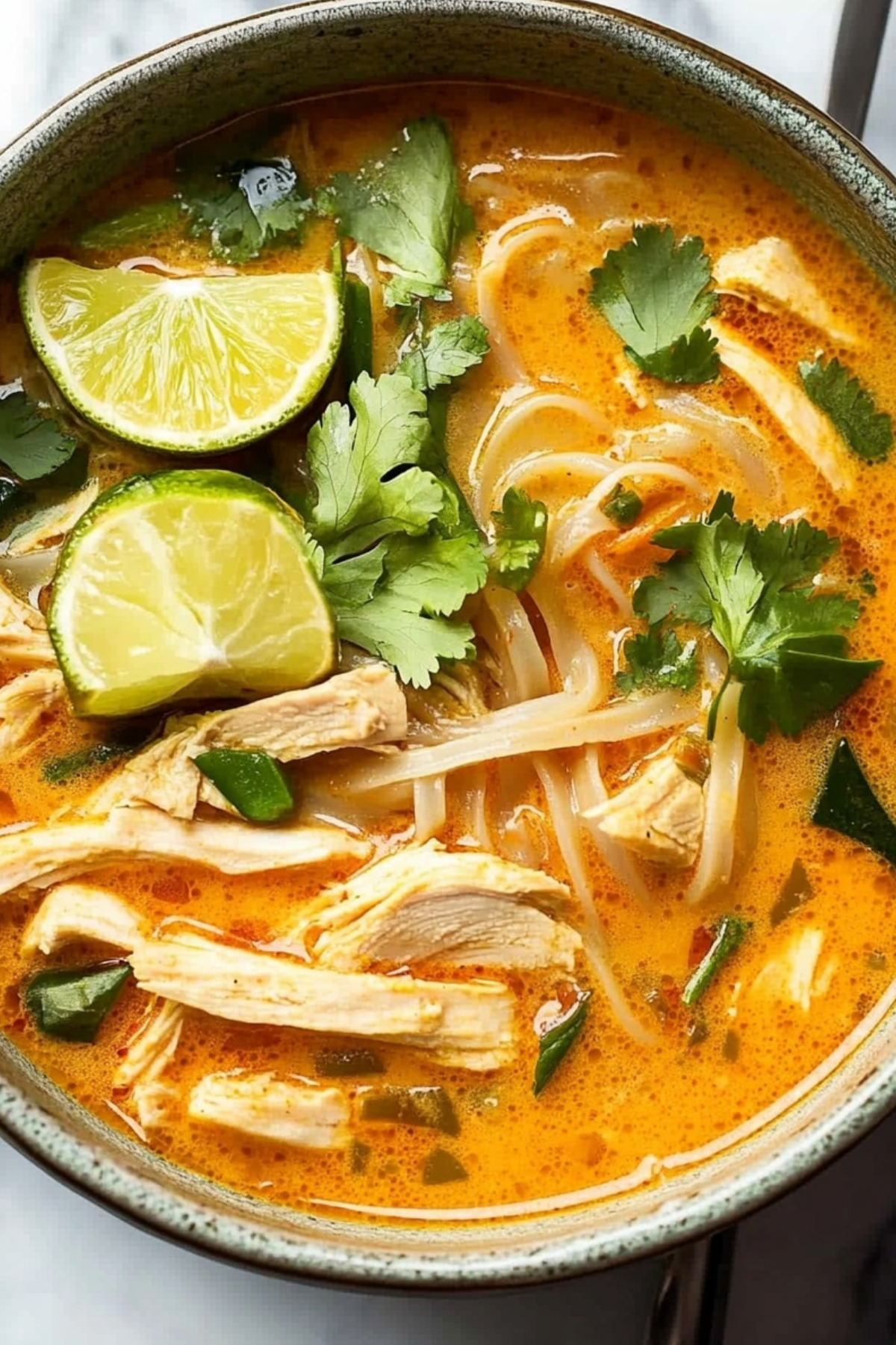 Thai Chicken Curry Soup in a bowl with fresh herbs and lime