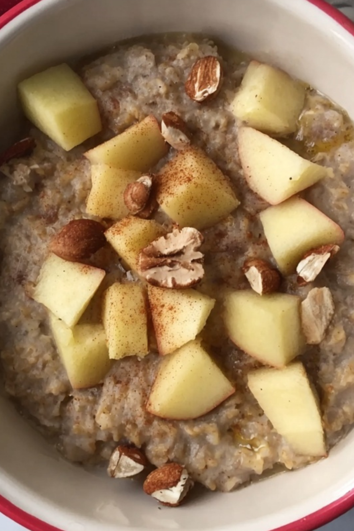 Bowl of apple and cinnamon porridge topped with almond butter and berries