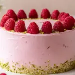 Raspberry Pistachio Cake topped with fresh raspberries and pistachio pieces