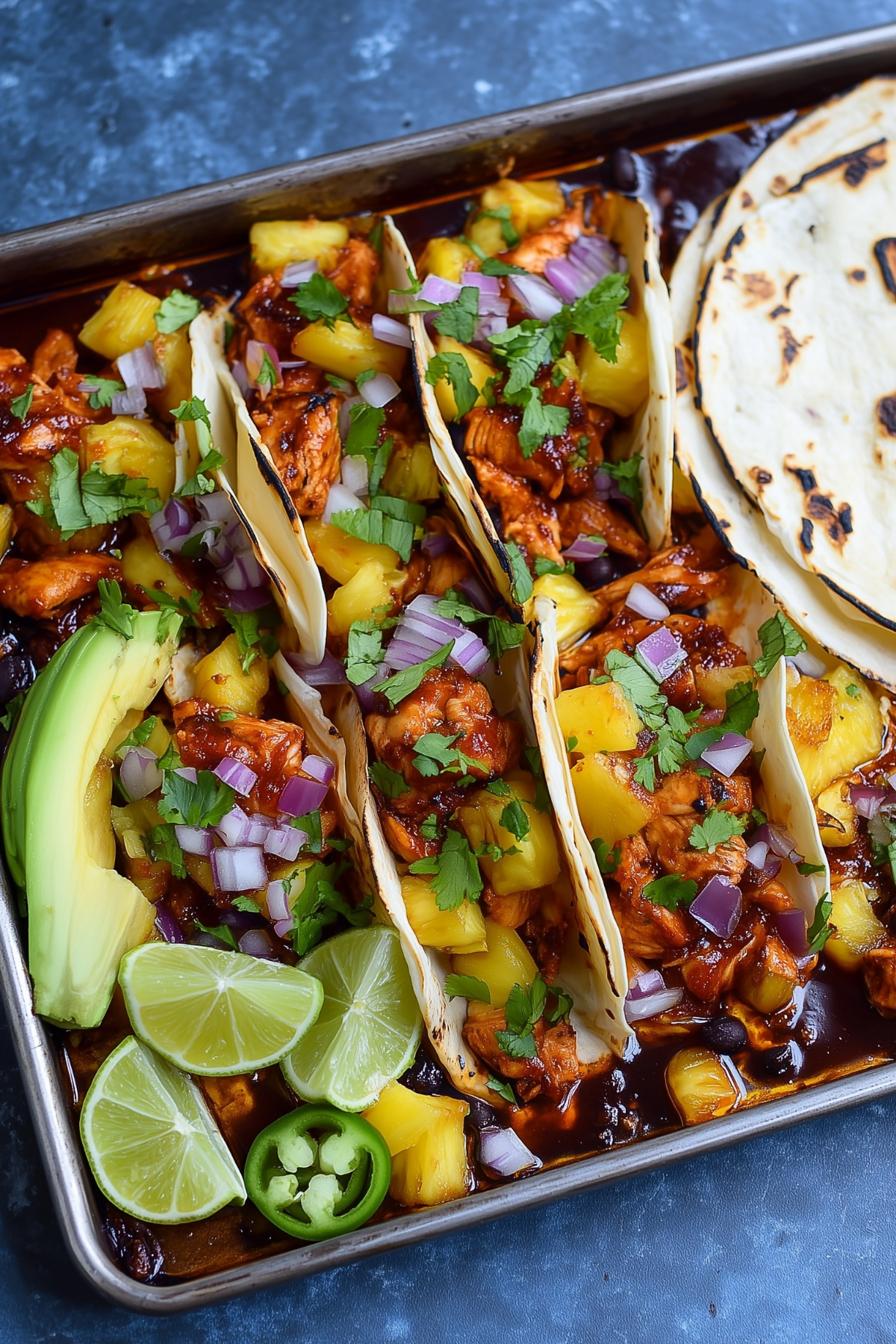 Delicious One Pan Chicken and Pineapple Tacos served with avocado and lime